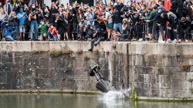 A statue being thrown into a river